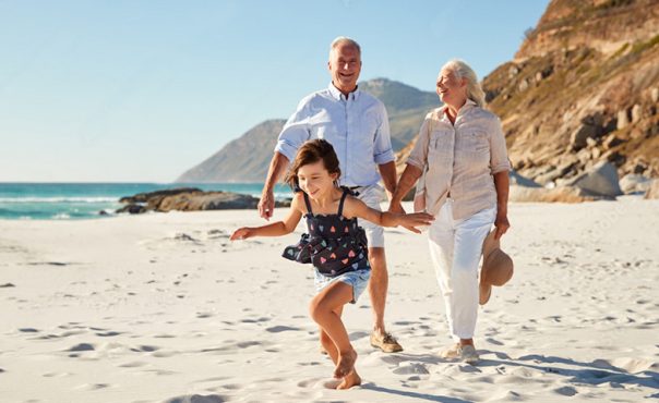 grandparents with kid walking on beach