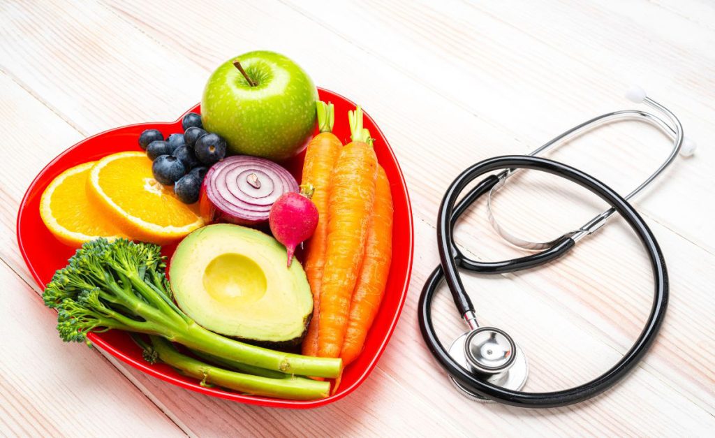 fruits and vegetables on a heart-shaped plate with stethoscope